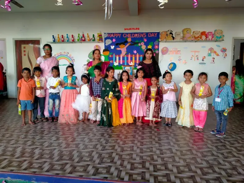 Children in colourful clothes stand with adults in front of a SMARTKiDZ board that reads Happy Children's Day.